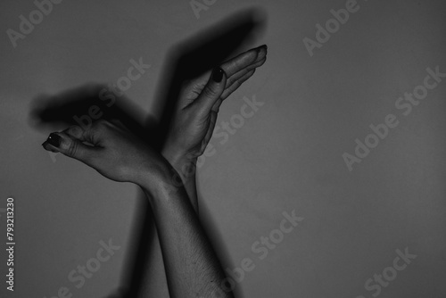 Female hands gesturing in the form of a bird on a light background in the dark under the light of a lantern