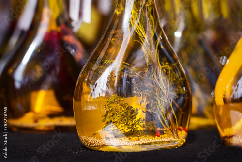 Close up. Olive oil in glass bottles, with herbs inside.