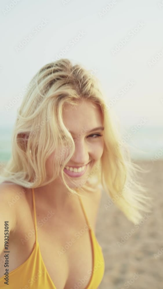 Vertical video of a happy young woman with camera in hand takes a selfie with her mobile phone smiling while enjoying a sunset on the beach in summer. POV camera point of view Vertical video of a happy young woman with camera in hand takes a selfie with her mobile phone smiling while enjoying a sunset on the beach in summer. POV camera point of view