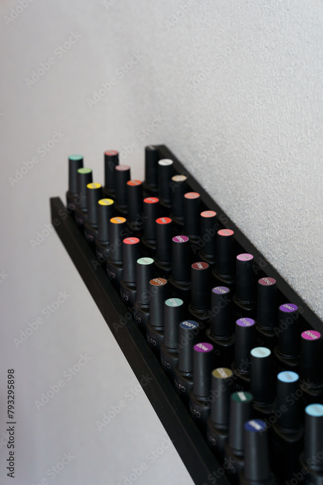 Fototapeta premium Shelves with black bottles with gel nail polish
