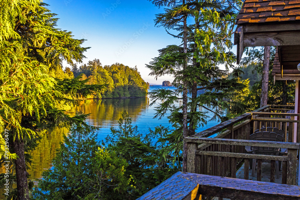 Obraz premium View of a bay surrounded by horse trees from the balcony of a cottage, West Coast of Vancouver Island near Ucluelet. Calm water, rocky island in the distance