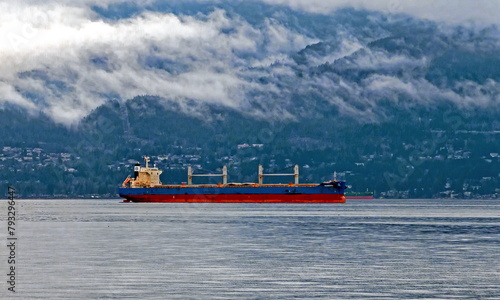 Vancouver Harbour, West Vancouver, an ocean tanker awaits loading at the port on a cloudy day with West Vancouver and a cloud-covered mountain landscape in the background