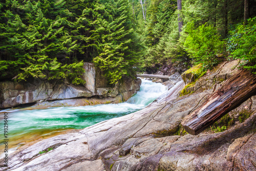 A stream flowing along the rocky bottom of a narrow and deep canyon covered with green forest. This place is located in the Golden Ears Park, Maple Pidge, Vancouver