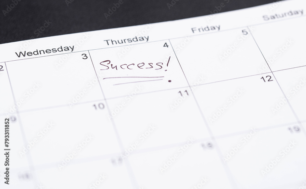 Hand fills in a large wall calendar, marking 'Success' - the concept of setting and achieving goals. Hand fills in a large wall calendar, marking 'Success' - the concept of setting and achieving goals.