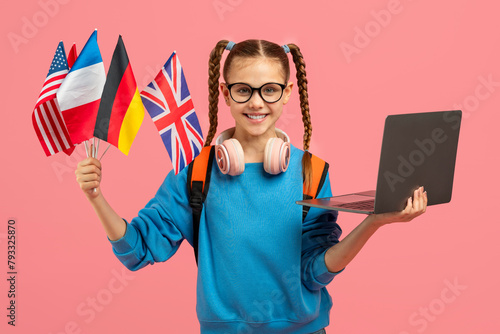 Teenager with laptop and international flags on pink background photo