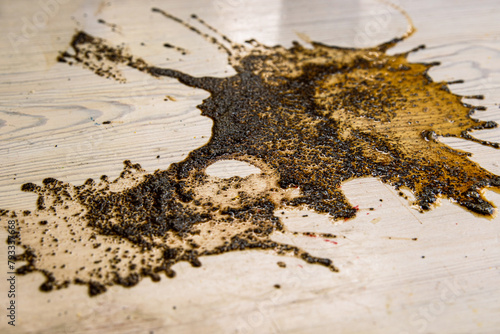 Coffee stains on white wooden table. Wood texture background. Big dark brown dramatic Splatter, fleck, splash, spot, drops of black coffee. Pattern, wallpaper. Top view.  Closeup. Copy space.