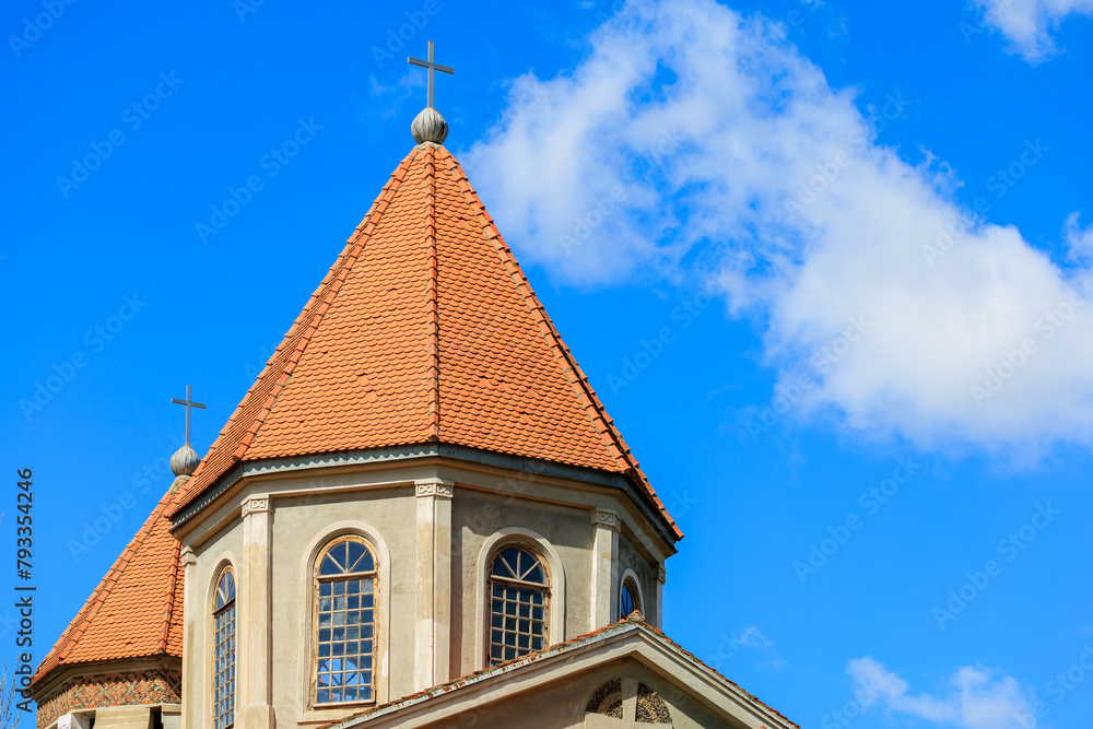 A church steeple with a red roof and two crosses on top