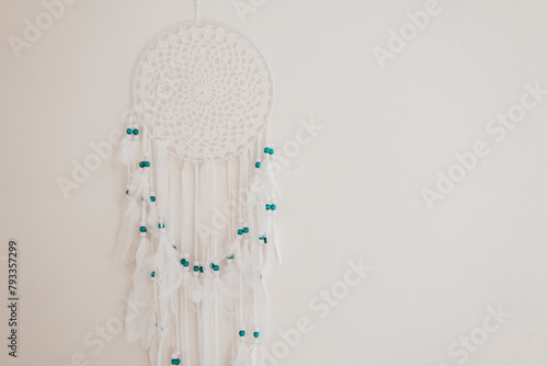 Dream Catcher with white feathers and blue beads on a beige wall.Wicker talisman protects against bad dreams. Decoration for home and room. Macrame wall decoration 