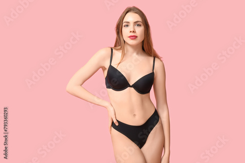 Attractive young woman in black underwear on pink background