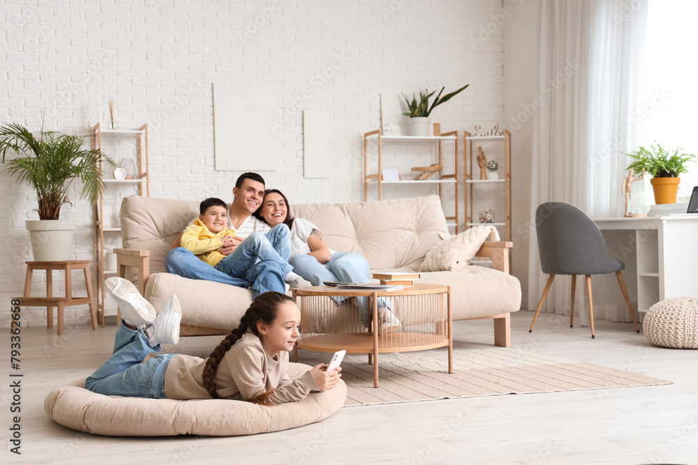 Little girl using mobile phone while her family watching TV at home Little girl using mobile phone while her family watching TV at home