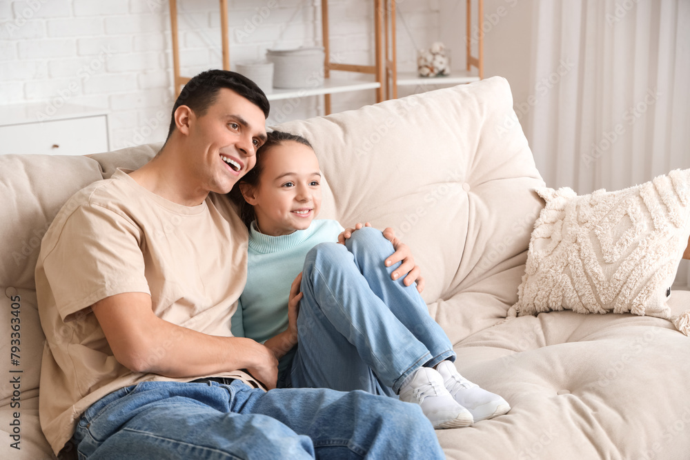 Happy father with his little daughter watching TV on sofa at home Happy father with his little daughter watching TV on sofa at home