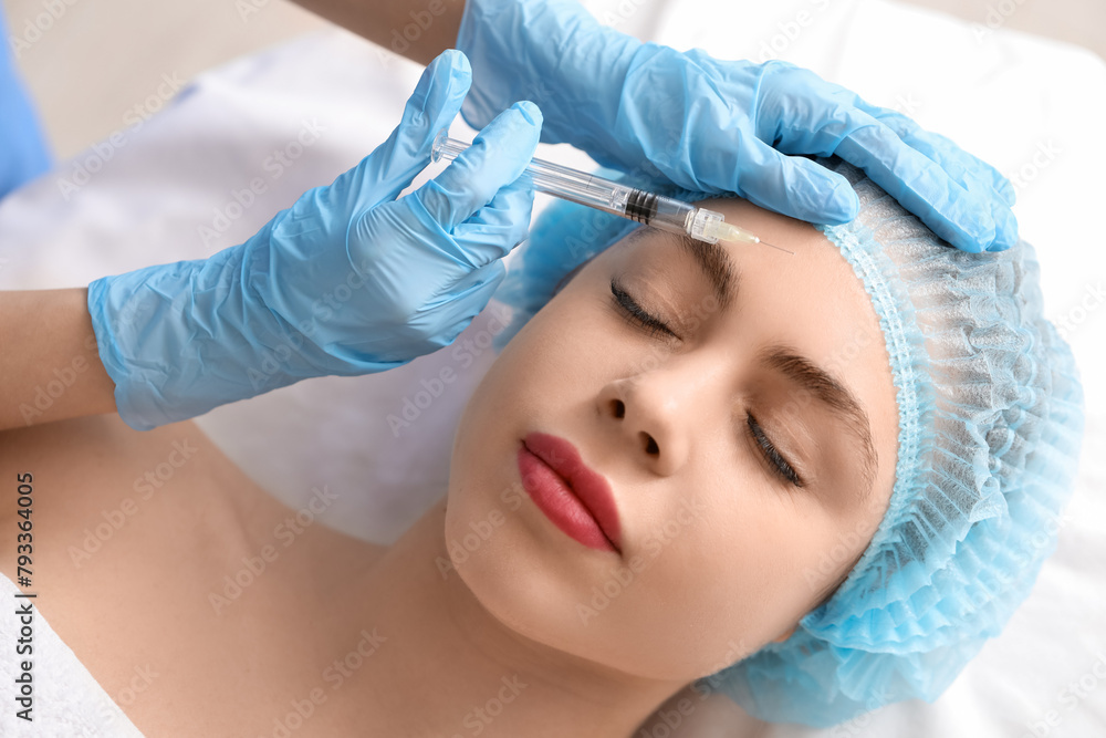 Pretty young woman receiving filler injection in beauty salon Pretty young woman receiving filler injection in beauty salon