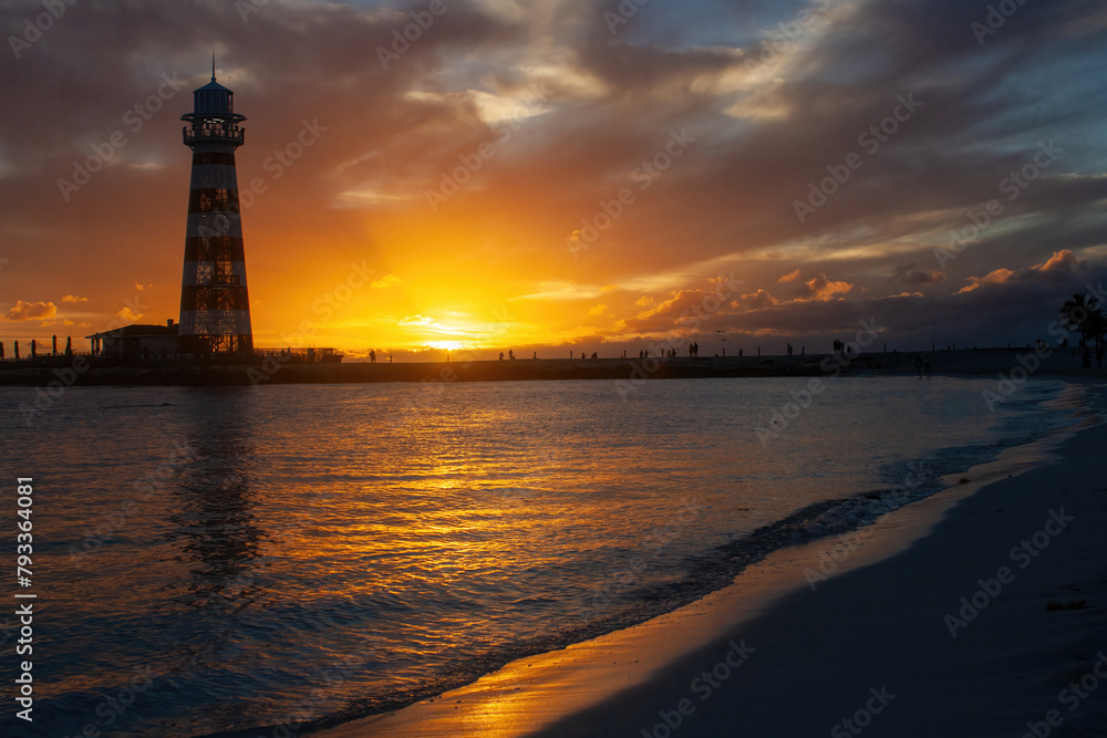 Horizontal shot of a summer dusk. The orange sky with the sun dipping to the horizon behind the clouds. Lighthouse backlit.Summer holiday concept