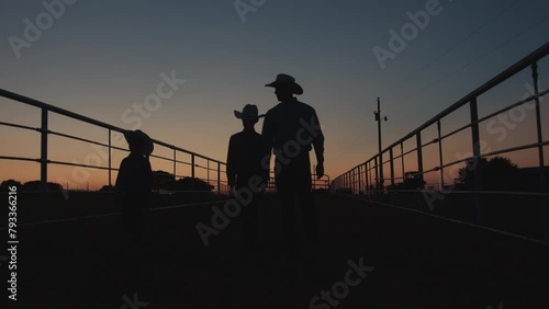 Silhouette shot of young farmers clipping on pasture gates to watch the sunset