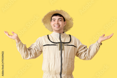 Male beekeeper in straw hat on yellow background photo