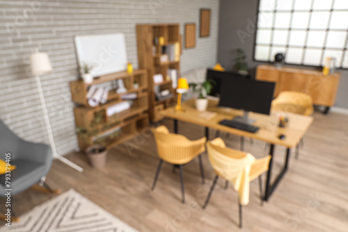 Blurred view of stylish office with workplace, shelf units and plants © Pixel-Shot