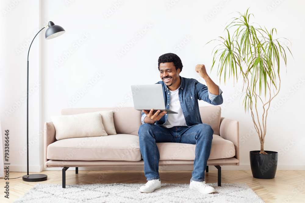 Black man excitedly using laptop at home Black man excitedly using laptop at home