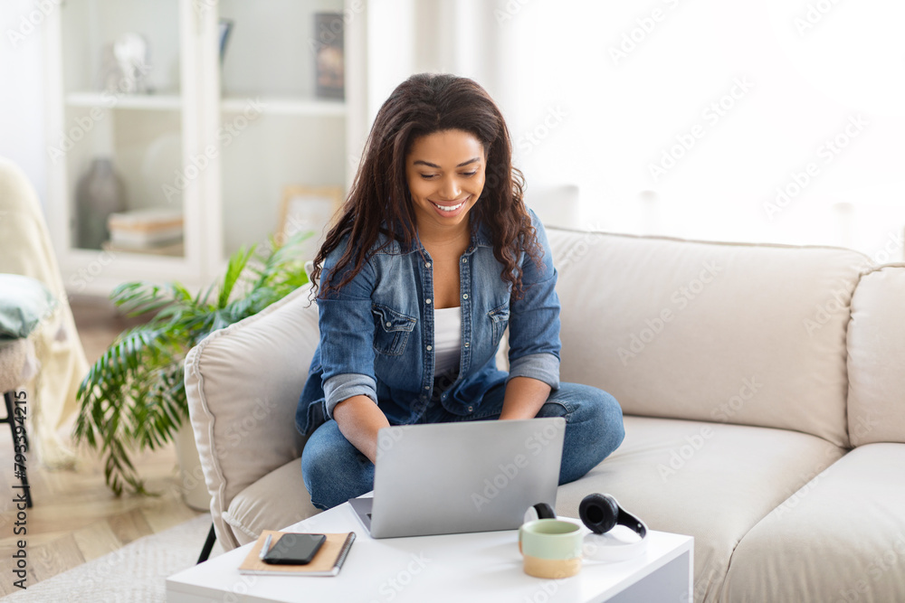 African American Young Woman Sitting on Couch Using Laptop African American Young Woman Sitting on Couch Using Laptop