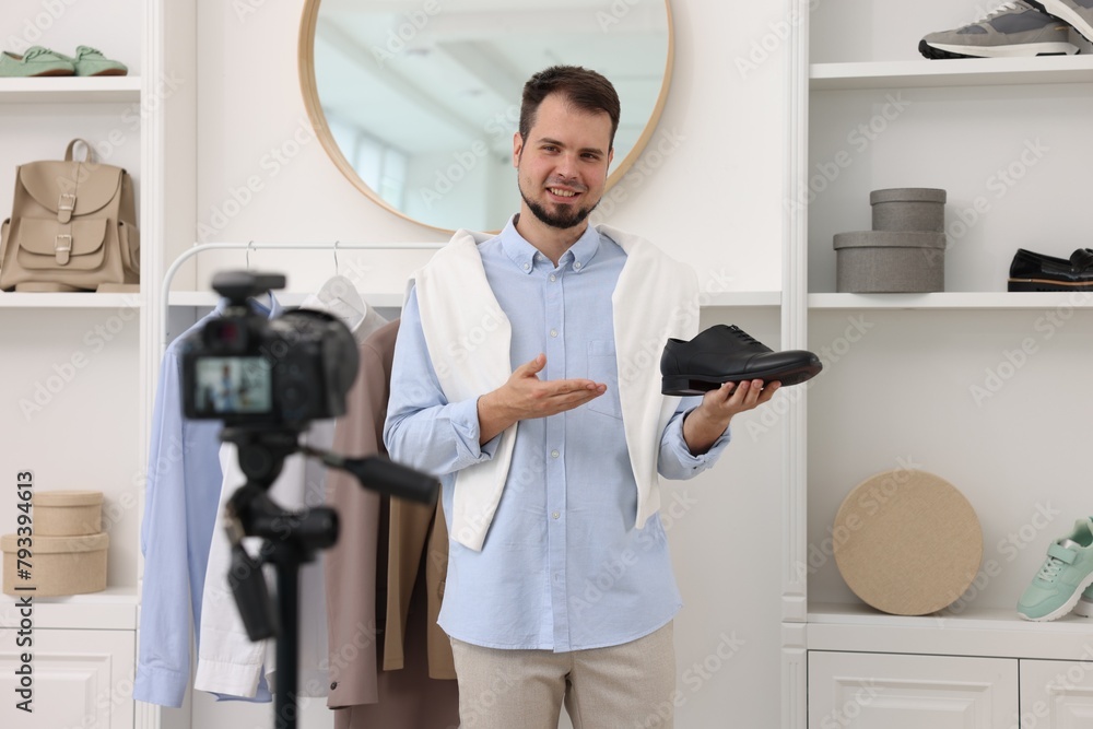 Smiling fashion blogger showing shoe while recording video at home