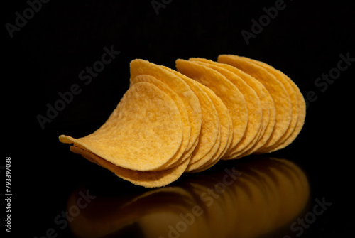Close-up with a few (a bunch) of potato chips on a black background