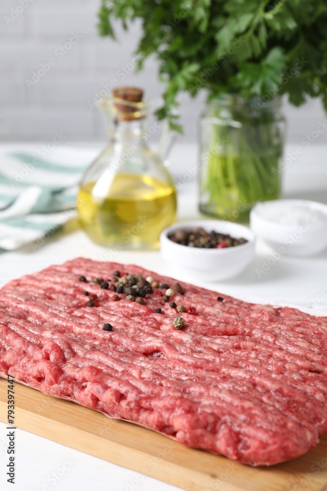Raw ground meat, spices, oil and parsley on white table Raw ground meat, spices, oil and parsley on white table