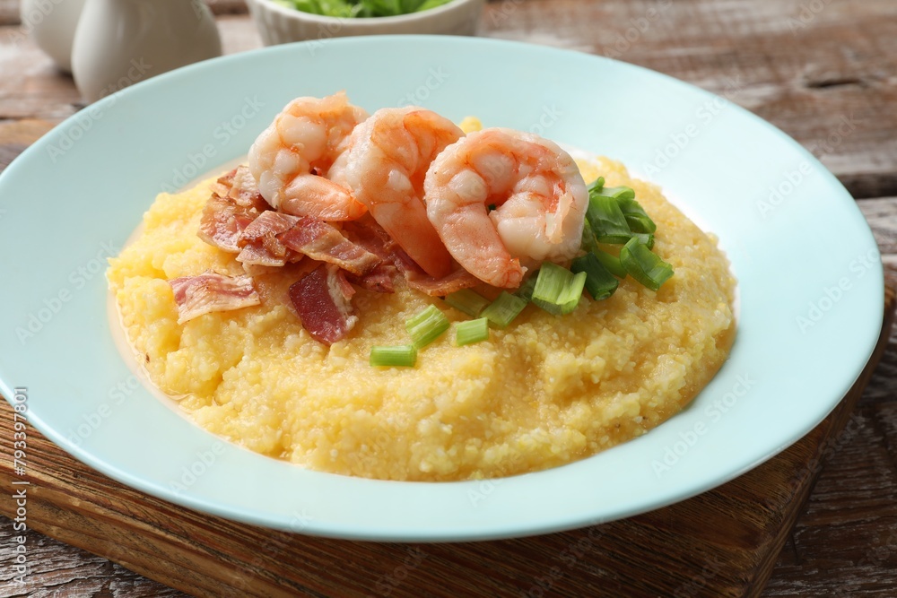 Plate with fresh tasty shrimps, bacon, grits and green onion on wooden table, closeup Plate with fresh tasty shrimps, bacon, grits and green onion on wooden table, closeup
