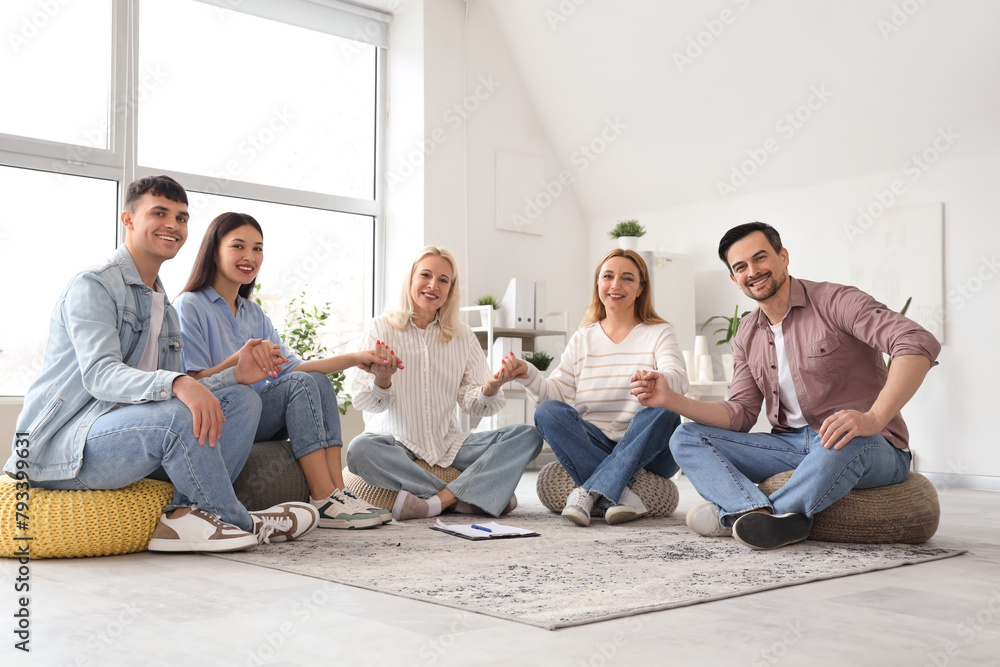 Fototapeta premium People on poufs holding hands at group therapy session