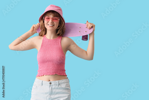 Beautiful young happy woman with skateboard on blue background © Pixel-Shot