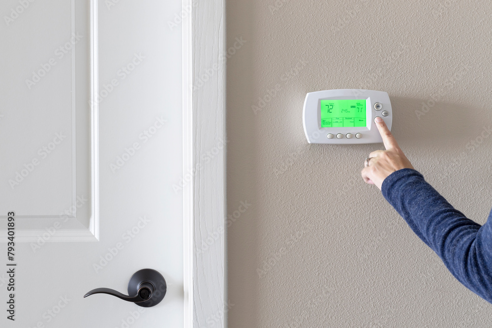 Programmable thermostat with display light on. Adjusting thermostat in the room Programmable thermostat with display light on. Adjusting thermostat in the room