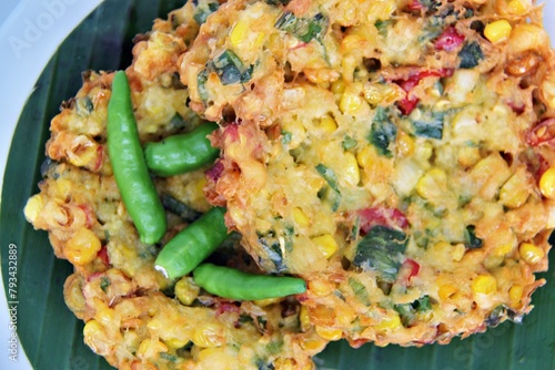 Bakwan Jagung or Dadar Jagung or Dadar Jagung Manado, is Manadonese style of corn fritters. Savoury snack made of corn, egg, flour, spring onion, pepper and salt. Served on a wooden plate. photo