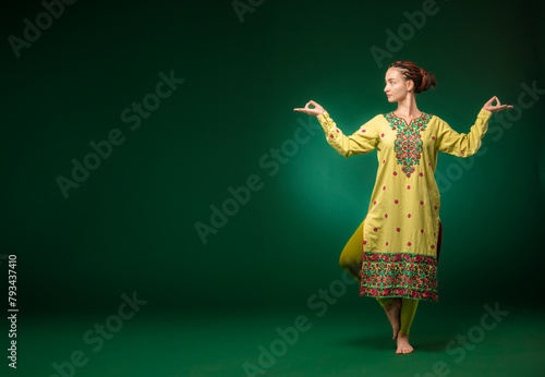 girl in a green sari in a yoga pose on a green background in full growth