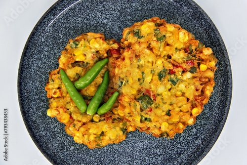 Bakwan Jagung or Dadar Jagung or Dadar Jagung Manado, is Manadonese style of corn fritters. Savoury snack made of corn, egg, flour, spring onion, pepper and salt. Served on a wooden plate. photo