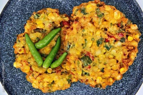 Bakwan Jagung or Dadar Jagung or Dadar Jagung Manado, is Manadonese style of corn fritters. Savoury snack made of corn, egg, flour, spring onion, pepper and salt. Served on a wooden plate. photo