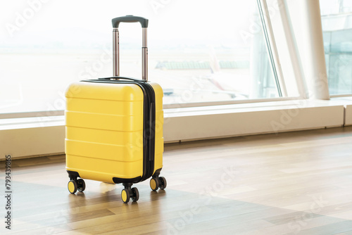 Yellow luggage bag on wheels at the airport, side view.
