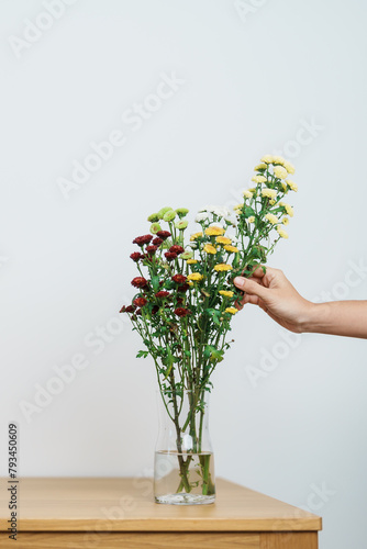 Woman hand arrange Colorful flowers bouquet in mason jar on table background. Happy day with fresh flower