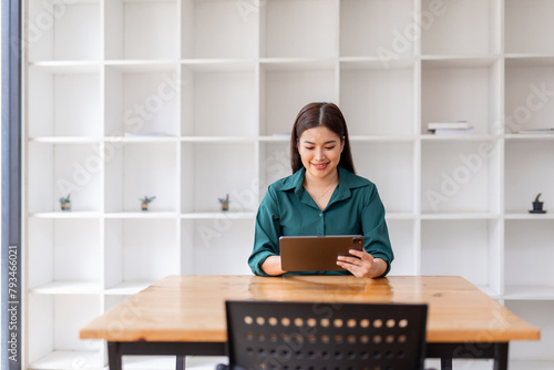 Portrait of Young asian business woman using tablet, standing in the office workplace. © David