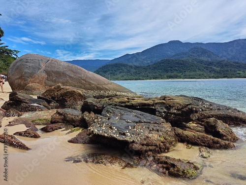 Pelado Island in Paraty, mountains in the background,sky with clouds, large rocks, and calm sea. Natural swimming pool and warm water