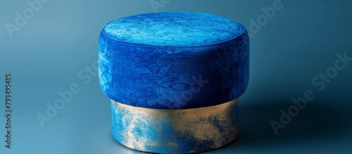 A single blue stool with elegant gold trim is placed in front of a solid blue background