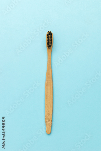 Wooden toothbrush with black bristles on a blue background.