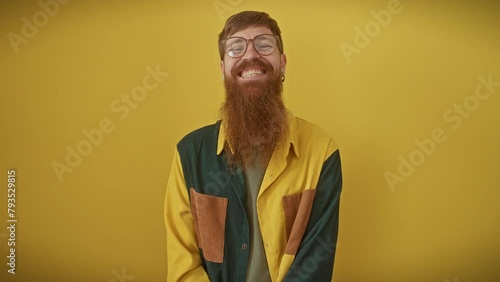 Comical young redhead guy wearing glasses, making a crazy fish face gesture. funny expression with puckered lips over yellow background! photo