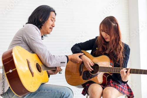 Young Asian teenager is learning to play guitar by professional teacher who showing simple chords for music class school