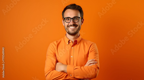 A cheerful millennial man wearing glasses, hands folded, on a bright orange backdrop © tahira