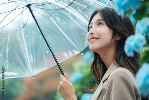 梅雨の晴れ間、雨があがった空を傘を差しながら見上げる通勤中の若いol・会社員・日本人女性(美人モデル)と青い紫陽花