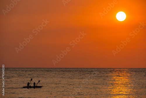 Two people paddling a kayak, skyline landscape background Sunset in the evening sky with colorful clouds and beautiful cloud patterns in the soft evening light at the sea. photo