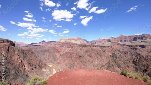 pan of Grand Canyon on sunny day with muddy Colorado River
