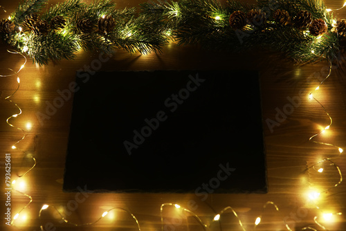 Christmas fir tree with decoration on dark wooden board background. Border art design with Christmas tree