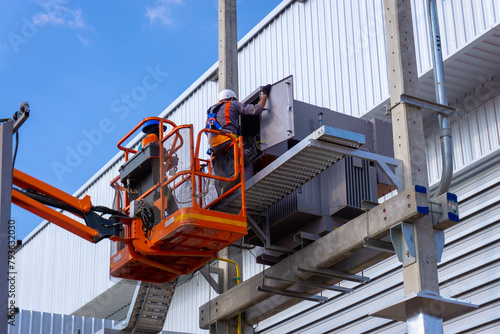Electrical engineers working on boom lift for inspection power transformer at site construction 