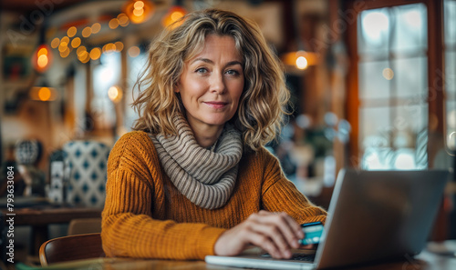 portrait of a middle aged woman with laptop and a credit card making online order, online shopping purchasing with card 