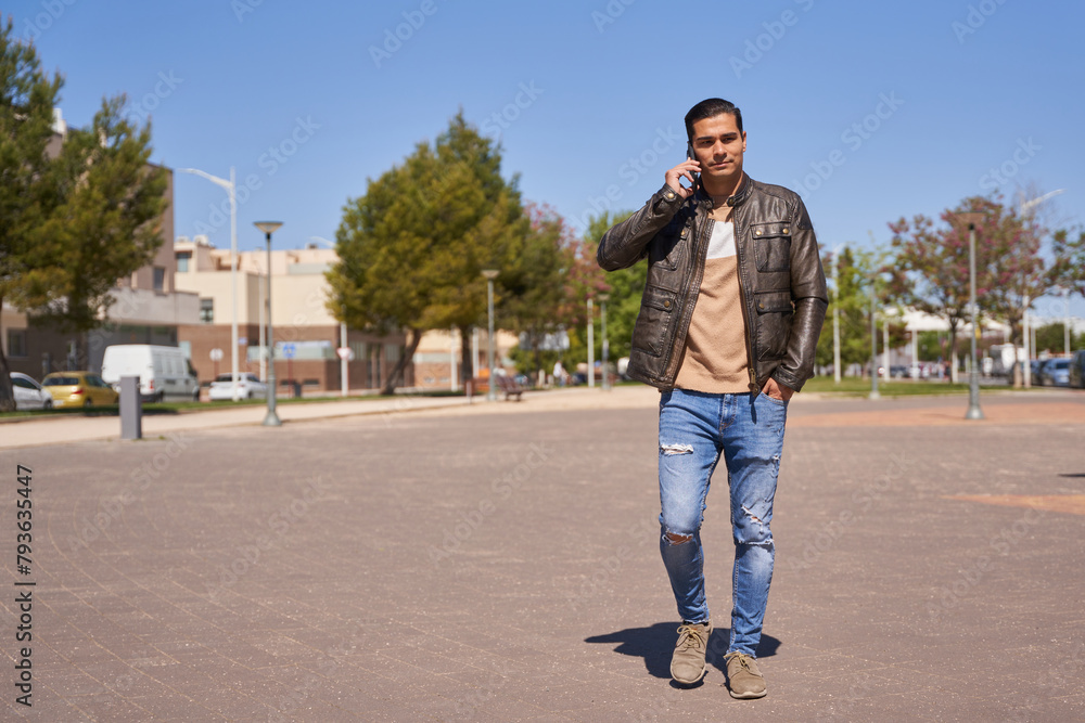 Handsome man talking on the phone while walking on the street Handsome man talking on the phone while walking on the street