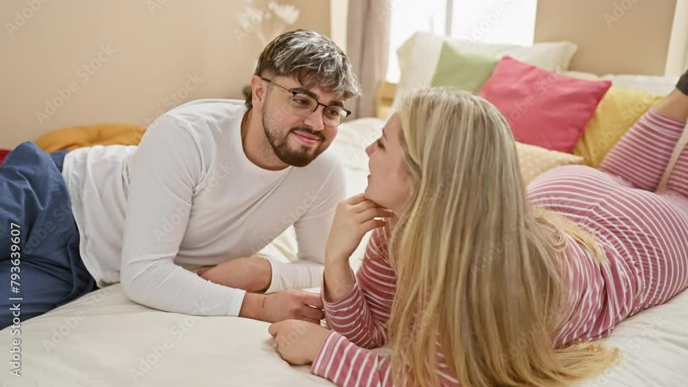 A smiling couple laying on a bed in a cozy bedroom with colorful pillows in the background, sharing an intimate moment. A smiling couple laying on a bed in a cozy bedroom with colorful pillows in the background, sharing an intimate moment.